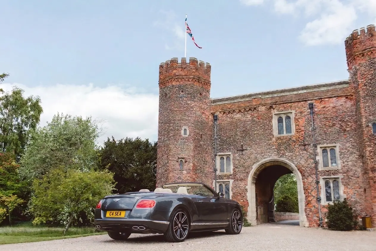 Bentley convertible parked at the gatehouse of an English castle